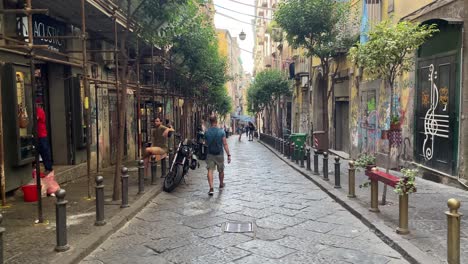 Tourists-explore-Spaccanapoli,-the-most-famous-straight,-narrow-and-charming-street-in-Naples,-Italy
