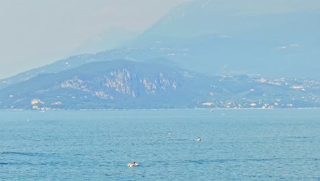 Leisure-boats-on-Lake-Garda,-majestic-mountain-background