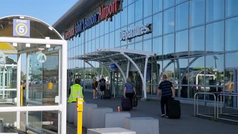 Passengers-entering-Liverpool-John-Lennon-airport-departure-doors-pulling-luggage-suitcase
