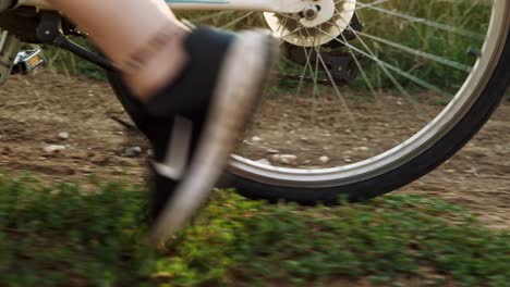 Close-up-of-feet-pushing-bike-on-golden-hour-sunlit-rural-track-slow-mo