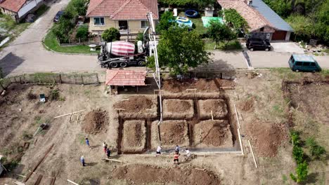 Ready-mix-concrete-delivery-to-building-plot-trench-foundation-drone-shot