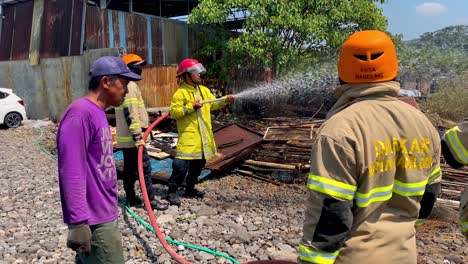 Bombero-Indonesio-Sosteniendo-Una-Manguera-Y-Extinguiendo-El-Fuego,-Cámara-Lenta,-Portátil