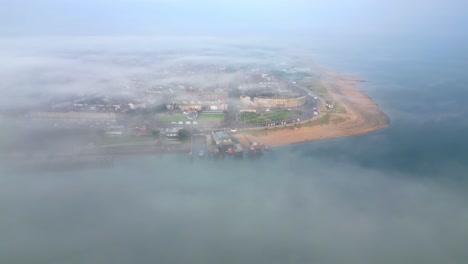 Flying-over-river-fog-bank-towards-mist-shrouded-headland-fishing-town-of-Fleetwood,-Lancashire,-UK