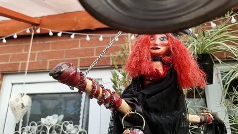 Hand-crafted-red-haired-witch-hanging-from-broomstick-in-home-garden-outdoor-shelter-sanctuary