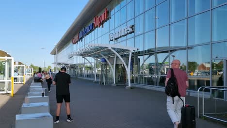 British-travellers-entering-Liverpool-John-Lennon-airport-departure-doors-pulling-luggage-suitcase