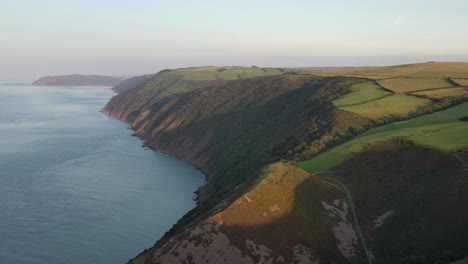 Drohnenaufnahme,-Die-Sich-Von-Rechts-Nach-Links-Dreht-Und-Dabei-Auf-Die-Nordküste-Von-Devon-Und-Einen-Sonnenuntergang-Im-Vereinigten-Königreich-Blickt
