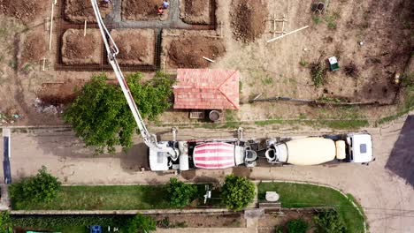 Vista-De-Arriba-Hacia-Abajo-De-Camiones-Mezcladores-De-Cemento-Que-Entregan-Concreto-Al-Terreno-De-Construcción