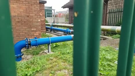 British-clean-water-supply-industrial-distribution-pipes-and-pumps-at-recycling-substation-secured-behind-metal-fence