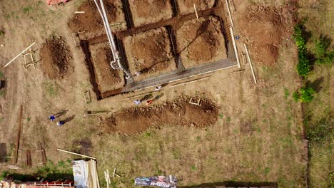 Camión-De-Cemento-Con-Pluma-Vierte-Hormigón-Premezclado-En-Una-Zanja-Excavada-Vista-Por-Drones