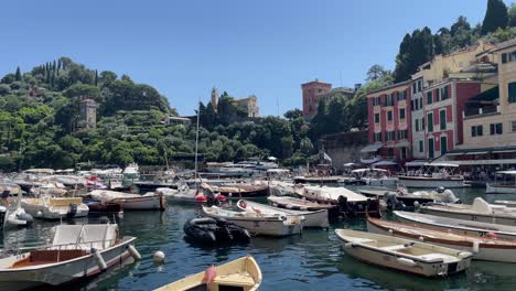 Boote-Legen-Nebeneinander-Im-Kleinen-Hafen-Von-Portofino,-Italien,-An-Und-Im-Hintergrund-Sind-Die-Wahrzeichen-Von-Chiesa-Di-San-Giorgio-Zu-Sehen