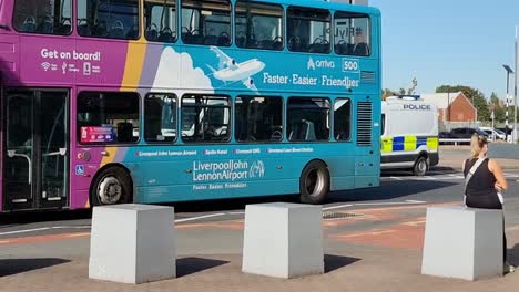 Bus,-Der-An-Einem-Polizeiwagen-Der-Britischen-Grenzpolizei-Vorbeifährt,-Der-Vor-Dem-John-Lennon-Liverpool-Flughafen-Geparkt-Ist