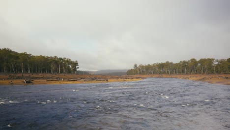 Fluss-Mit-Abgeholztem-Rotem-Felsenufer-Und-Regenwald