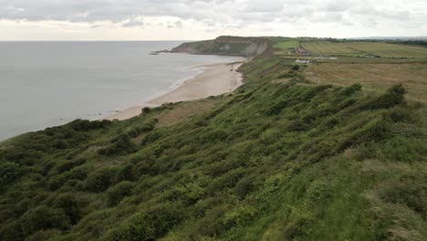 Aerial-drone-shot-over-Cayton-bay,-beach-and-village-North-Yorkshire,-cloudy-day