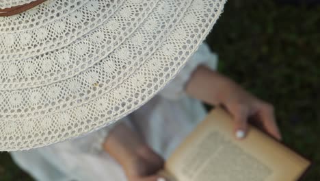 Girl-sits-in-white-sunhat-and-dress-reads-book-in-rural-peace-and-solitude