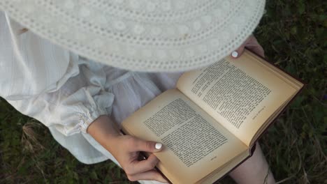 Book-lover-in-white-sunhat-and-dress-reading-novel-in-rural-tranquility