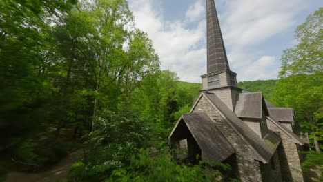 Cinewhoop-FPV-drone-footage-flying-through-a-forest-until-it-reaches-a-beautiful-church-with-a-steeple