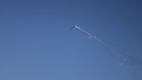 Pyrotechnical-aircraft-releasing-fireworks-from-one-wing-during-its-display