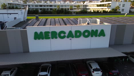 Aerial-view-of-Mercadona-grocery-store-with-solar-panels-on-the-rooftop,-green-energy-business-in-Marbella-Estepona-Malaga-Spain,-Spanish-supermarket,-4K-shot