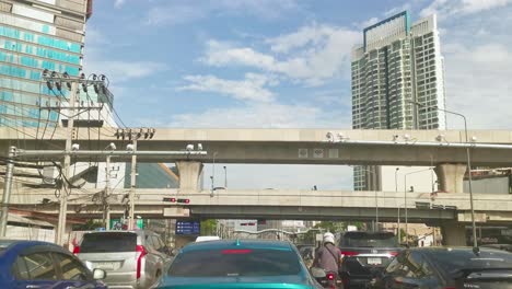 Hermoso-Día-Con-Una-Línea-De-Bts-Skytrain-Cruzando-En-Una-Intersección-Mientras-Espera-En-El-Tráfico-En-Ratchayothin,-Bangkok,-Tailandia