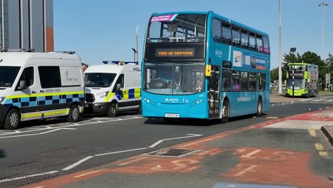 British-double-decker-city-bus-passing-parked-border-force-police-vans-outside-Liverpool-airport-Hilton-hotel