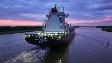 Under-colourful-skies-the-Vega-Daytona-cargo-ship-sails-on-river-Dortsche-Kil,-aerial