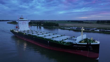 On-the-still-river-Dortsche-Kil-the-Vega-Daytona-container-ship-sails-onwards,-aerial