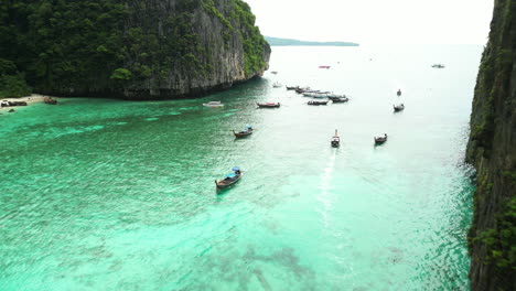 Barcos-Asiáticos-Tradicionales-De-Madera-Navegando-Por-Las-Aguas-Turquesas-De-La-Bahía-De-Pi-Leh,-Tailandia