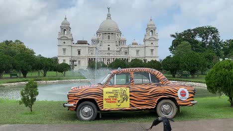 Statische-Aufnahme-Eines-Gelben-Taxis-Mit-Schwarzen-Streifen,-Das-Abends-Vor-Dem-Victoria-Memorial-In-Kalkutta,-Indien,-Für-Den-Schutz-Der-Tiger-Wirbt