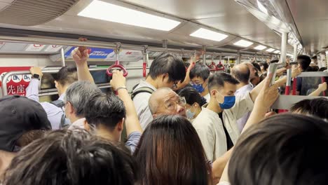 Cámara-Lenta-Dentro-Del-Abarrotado-Tren-Mtr-De-Hong-Kong-Con-Viajeros-Enmascarados-Durante-La-Hora-Pico