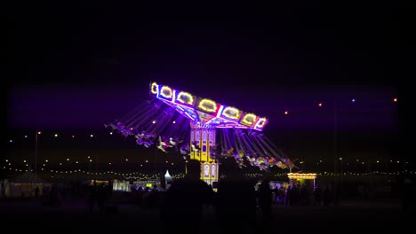 big-spinning-roller-coaster-ride-with-hoops-seats-spinning-around-in-the-middle-of-the-night-light-streaks-shining-lines-cinematic-feel-people-walking-around-and-pure-darkness-colourful-light-bulbs