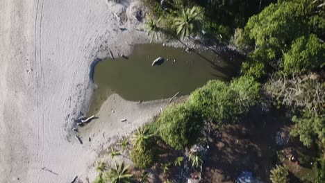 Slow-high-aerial-footage-overflying-the-natural-scenery-full-of-palm-trees-in-the-surf-beach-coast-of-Santa-Teresa,-Costa-Rica