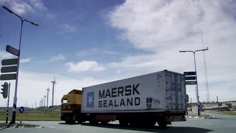 Container-LKW-Im-Hafen-Von-Rotterdam,-Panoramablick-Auf-Windkraftanlagen