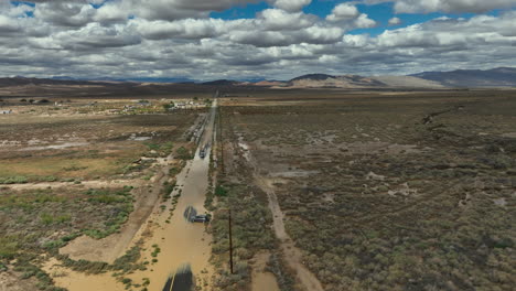 Flooded-Mojave-Desert-road-after-unseasonal-torrential-rains-leaves-a-vehicle-stranded---aerial-parallax