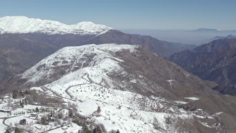 Dolly-In-Luftaufnahme-Der-Trockenen-Berge-Zentralchiles-Mit-Schnee-Auf-Den-Gipfeln-Und-Umweltverschmutzung-Im-Hintergrund-Im-Tal-Von-Santiago,-Chile
