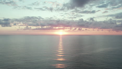 Sunset-over-calm,-crystal-clear-oceans-as-waves-roll-in