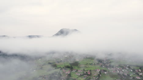 Aerial-flight-through-the-clouds-to-reveal-a-small-town-below-in-Valle-De-Bravo,-Mexico
