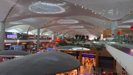 Beautiful-ceiling-view-from-Turkish-Airlines-business-lounge-onto-international-airport-in-Istanbul,-people-walking-around-shops-and-restaurants-in-Turkey,-busy-airport-with-luxury-stores,-4K-shot