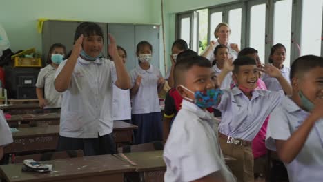 Glückliche-Kinder-In-Schuluniform-Tanzen-Vor-Freude-Im-Klassenzimmer