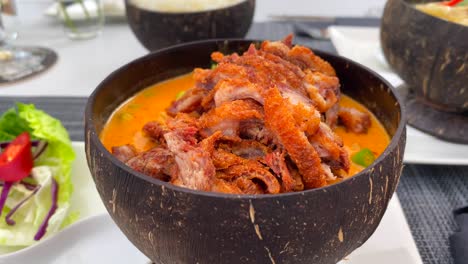 Tasty-traditional-Thai-red-curry-crispy-duck-dish-in-a-coconut-bowl,-Thai-cuisine-food-at-a-restaurant,-4K-shot