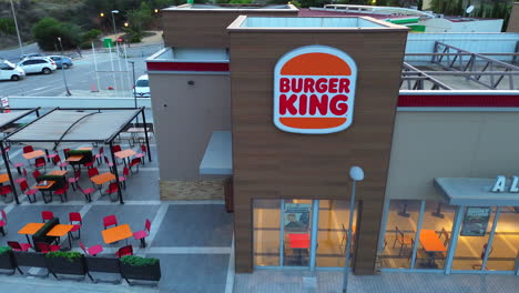 Aerial-view-of-Burger-King-fast-food-restaurant-entrance-in-Estepona-Spain,-outdoor-tables-and-chairs-dining-area,-4K-shot