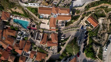Touristic-resort-in-Dhermi-in-Albania,-top-down-view-of-mountain-village-with-stone-houses-and-red-tile-roofs,-summer-vacation-top-spot-for-tourists