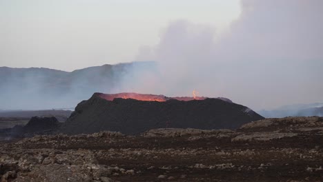 Wide-shot-showing-spewing-and-exploding-volcano-crater-with-rising-fumes-on-Iceland