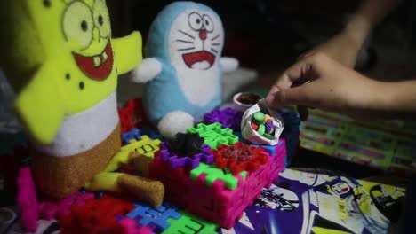 Las-Manos-De-Los-Niños-Juegan-Con-Bloques-Divertidos,-Muñecos-De-Bob-Esponja-Y-Muñecos-De-Doraemon,-Están-Felices-Y-Felices