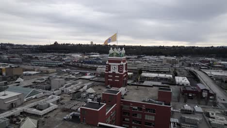 Slowly-circling-the-Starbucks-Coffee-building-in-Seattle,-revealing-the-city-skyline-cloudy-skys,-aerial