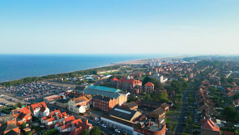 Witness-the-beauty-of-Skegness,-Lincolnshire,-through-this-aerial-cinematic-footage,-showcasing-its-extensive-beach,-lively-tourist-scene,-and-renowned-pier-on-a-summer-evening