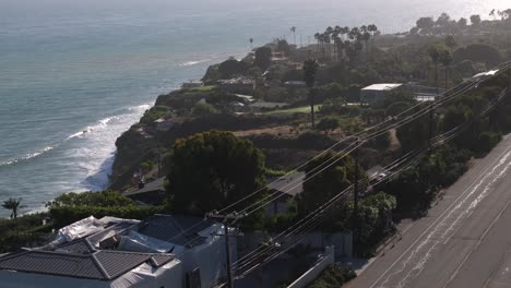 Aerial-telephoto-shot-rising-in-front-of-luxury-homes-on-the-coast-of-Malibu,-USA