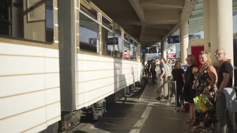 Abfahrt-Der-Straßenbahn-Vom-Bahnhof-In-Zeitlupe,-Während-Pendler-Auf-Die-Nächste-Ankunft-Warten