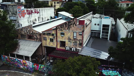 Toma-Aérea-De-Seguimiento-De-Graffiti-En-Las-Paredes-De-Un-Edificio-En-El-Callejón-Beco-Do-Batman,-Sao-Paulo,-Brasil.