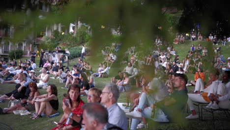 Crowd-of-People-Sitting-on-a-Grass-Lawn-in-a-Public-Park-During-Summer