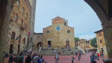 Persona-Caminando-Hacia-La-Piazza-Del-Duomo-Con-Palazzo-Comune-Y-La-Catedral-De-San-Gimignano-En-Italia